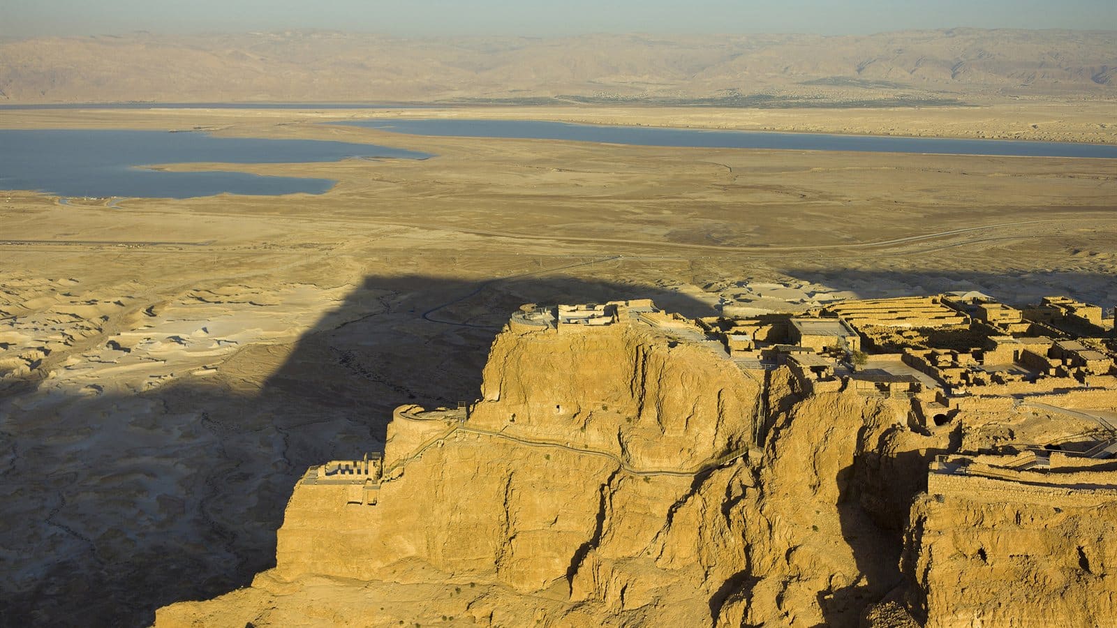 Aerial view of the Masada fortress plateau above the desert, with the Dead Sea in the distance