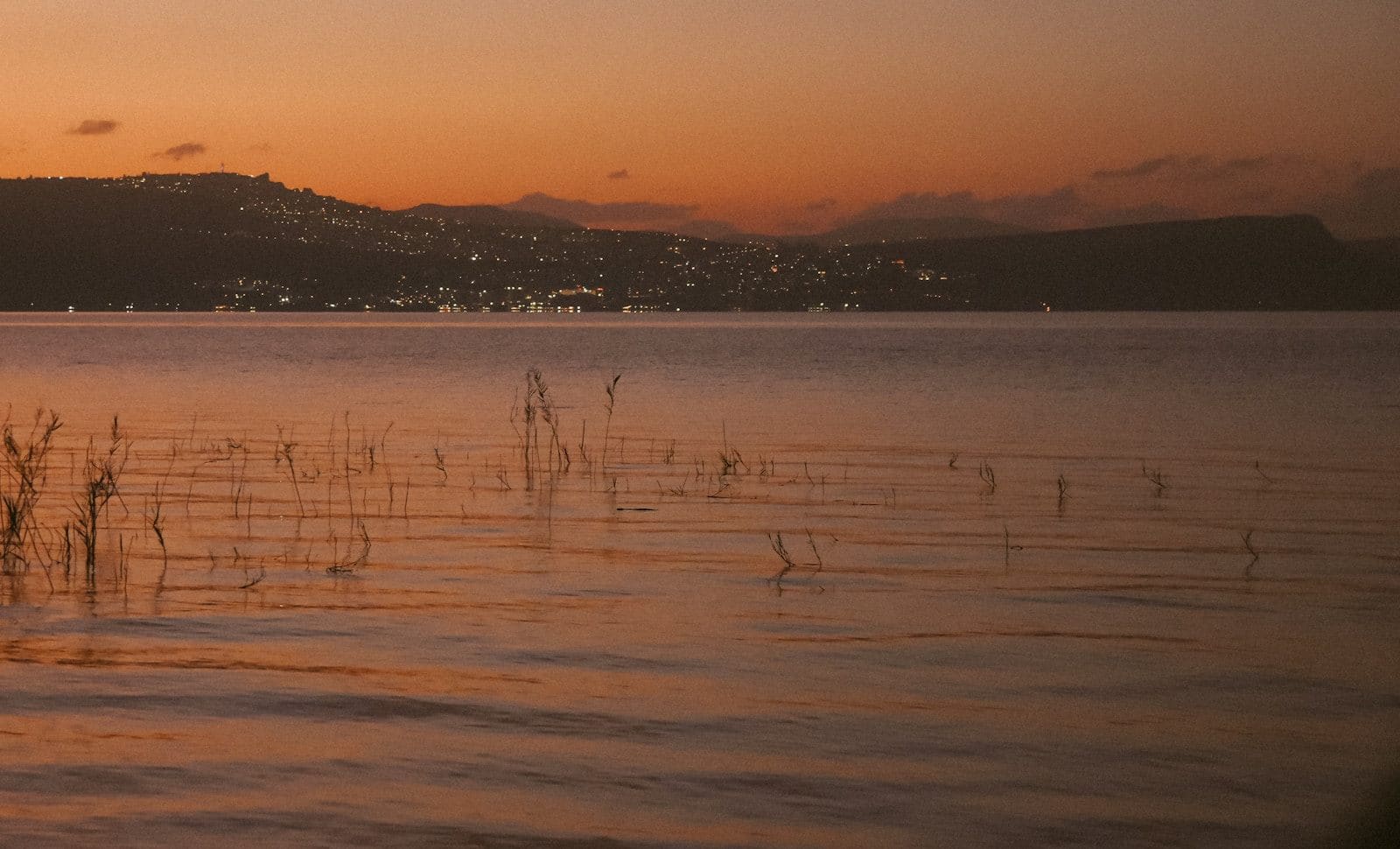 Sea of Galilee at sunset with hills silhouetted beyond the water