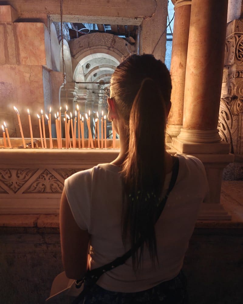 A visitor lighting a candle inside the Church of the Holy Sepulchre