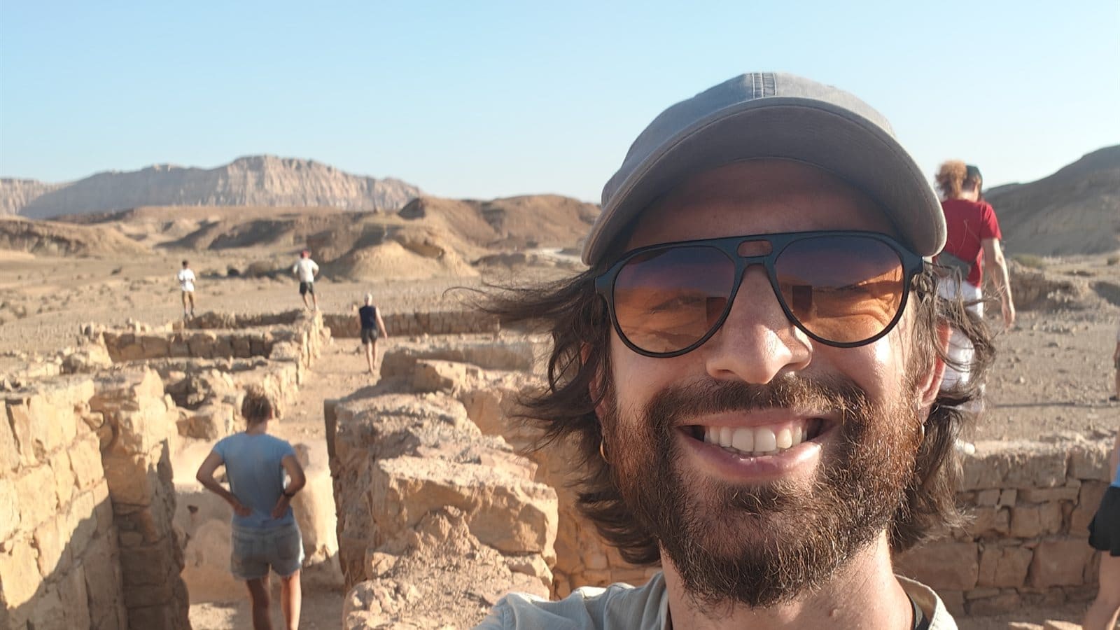 Ari smiling at the Nabataean ruins in Makhtesh Ramon, with his tour group behind him